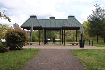 Natural surface trail from sports fields parking lot leads to covered picnic shelter and butterfly garden on paved surface